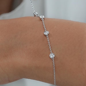 May include: A delicate silver chain bracelet with five small round clear stones.