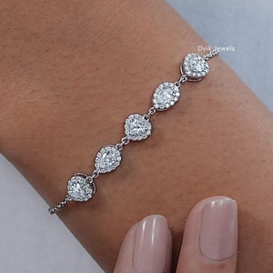 May include: A silver bracelet with a row of pear-shaped clear stones set in a halo of smaller stones.