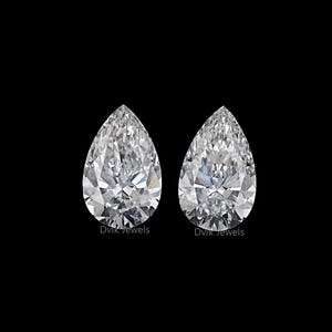 May include: Two pear-shaped diamonds in a clear display case with a black background. The diamonds are set in a silver setting.