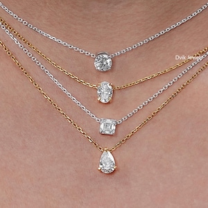 May include: Four delicate necklaces with diamond pendants. The necklaces are gold and silver, with different diamond shapes: round, oval, square, and pear. The chains are fine and elegant, creating a layered look.