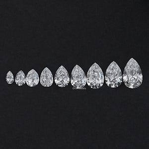 May include: A collection of nine pear-shaped diamonds of varying sizes, arranged in a row on a black background. The diamonds are clear and sparkling, with visible facets. The display is set within a black square frame.