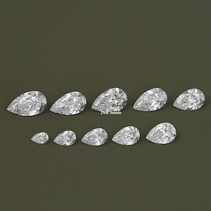 May include: A set of ten pear-shaped diamonds of varying sizes, arranged in a row on a green background.  The diamonds are clear and sparkly.