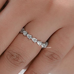 May include: A silver band ring with a pear-shaped diamond setting. The ring is set with multiple pear-shaped diamonds that are arranged in a continuous line around the band.