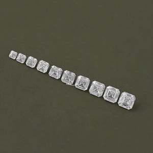 May include: A row of ten clear, square-shaped, princess cut diamonds of varying sizes, arranged from smallest to largest on a green background.