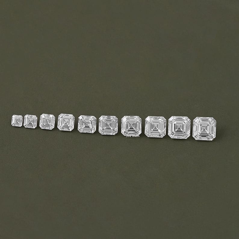 May include: A row of ten clear, square-shaped, faceted gemstones of varying sizes, arranged from smallest to largest.