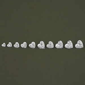 May include: A set of ten heart-shaped clear diamonds of varying sizes, arranged in a row from smallest to largest.