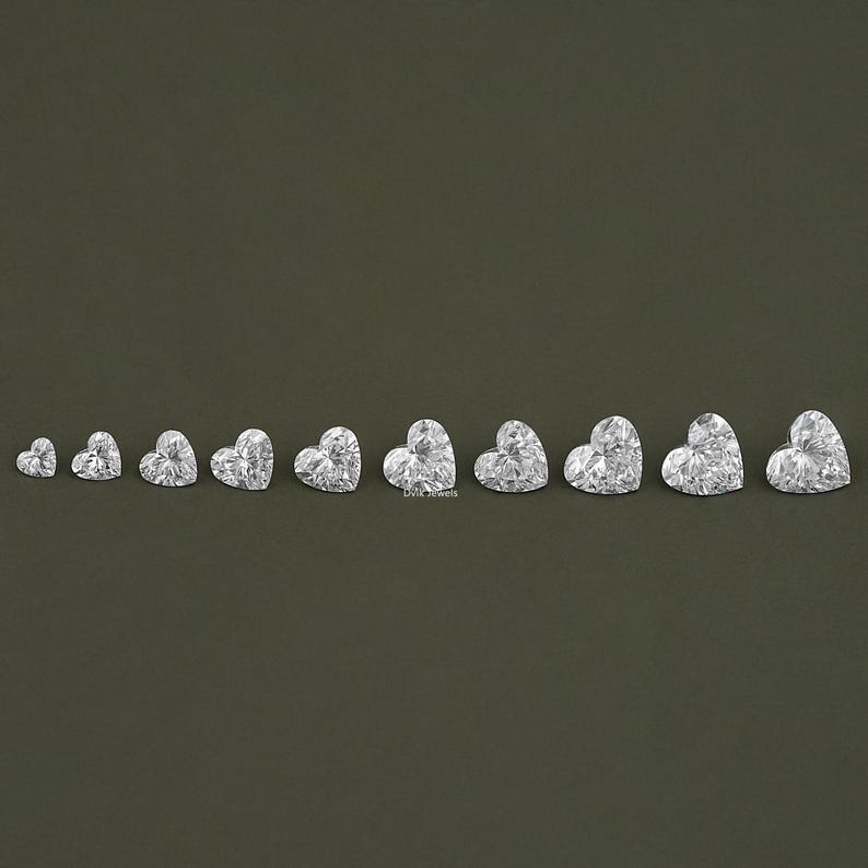 May include: A set of ten heart-shaped clear diamonds of varying sizes, arranged in a row from smallest to largest.