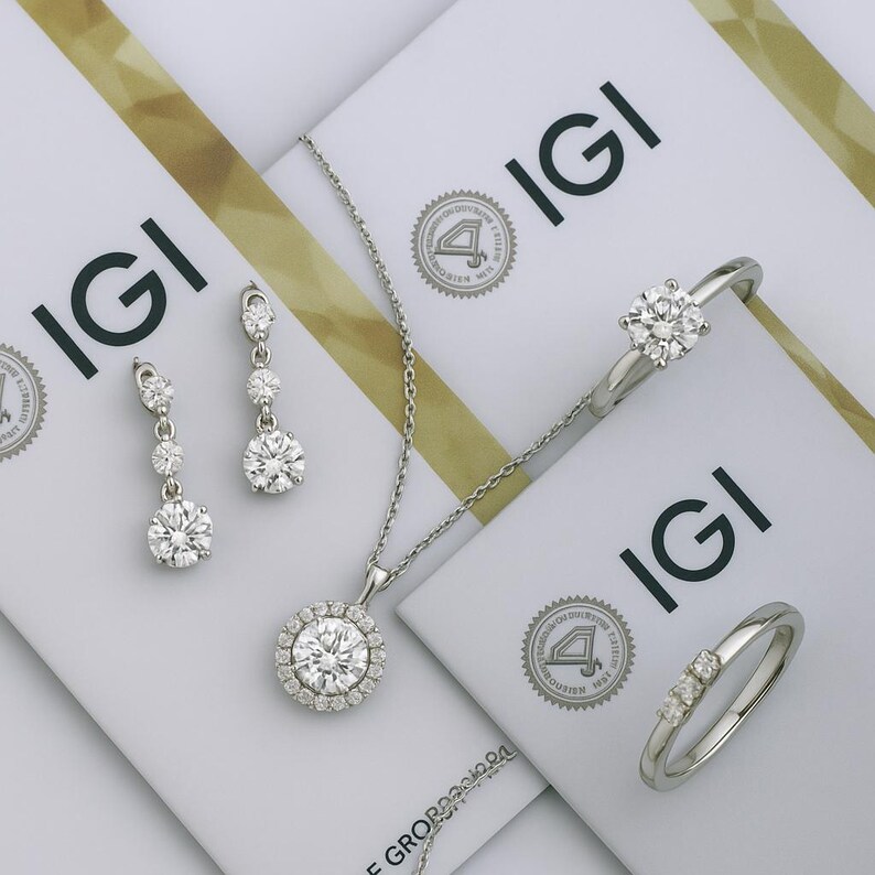 May include: A set of diamond jewelry featuring a pendant necklace, earrings, and two rings. The jewelry is set in silver and features round brilliant cut diamonds. The jewelry is displayed on a white background with IGI certification cards.