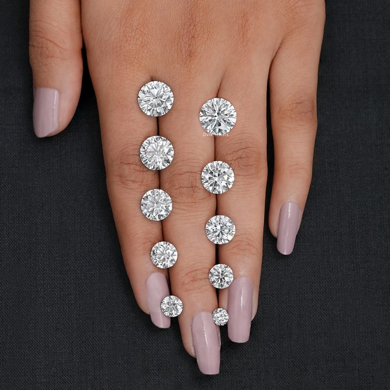May include: A hand model displays a set of round, clear diamonds of varying sizes. The diamonds are arranged in a row on the fingers of the hand, with the largest diamond at the top and the smallest diamond at the bottom.