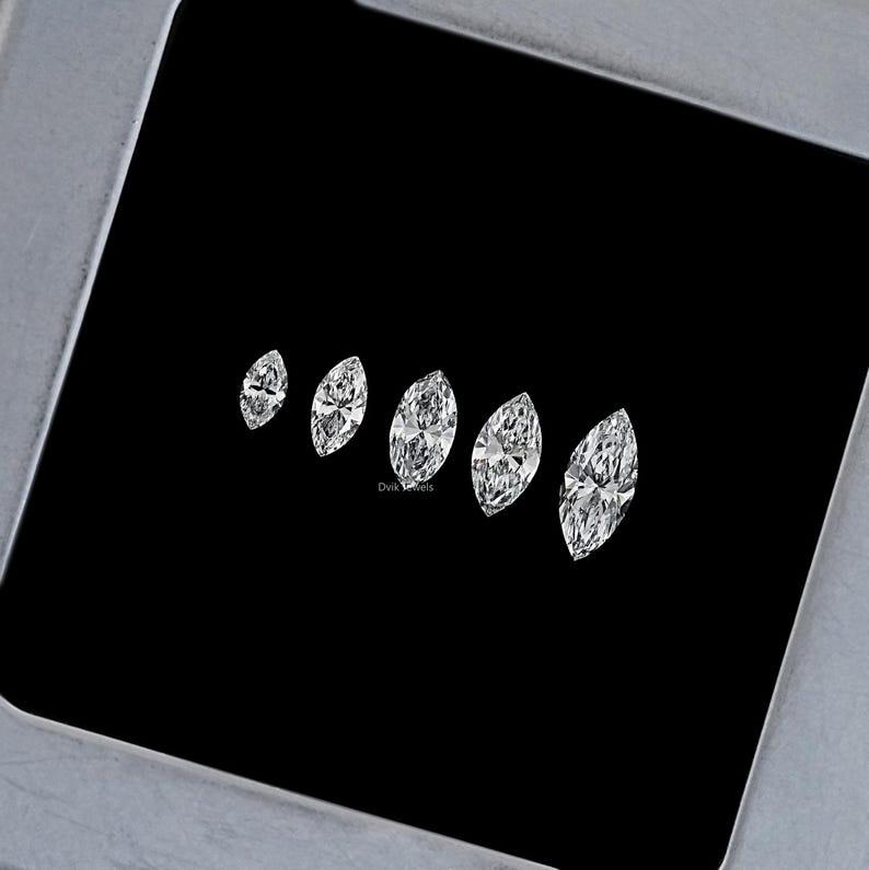 May include: Five marquise-shaped diamonds of varying sizes arranged in a row on a black background. The diamonds are clear and brilliant.