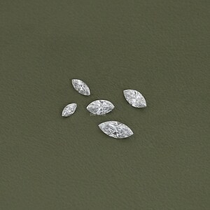 May include: Five clear marquise-shaped diamonds on a green background.