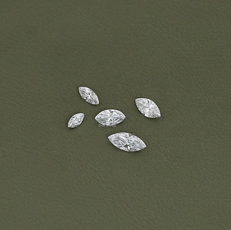 May include: Five clear marquise-shaped diamonds on a green background.