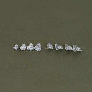 May include: A set of ten clear heart-shaped gemstones of varying sizes. The gemstones are arranged in a row from smallest to largest.