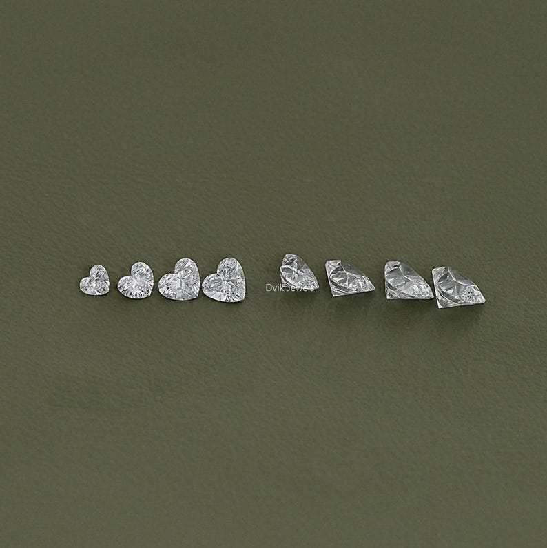 May include: A set of ten clear heart-shaped gemstones of varying sizes. The gemstones are arranged in a row from smallest to largest.