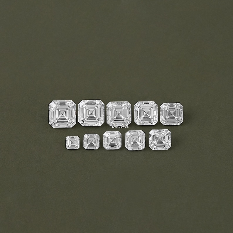 May include: Assortment of clear, square-shaped, faceted gemstones of varying sizes. The gemstones are arranged in a row from largest to smallest. The text "Dvik Jewels" is visible in the image.