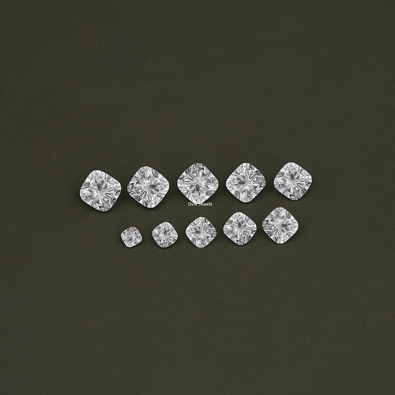 K&ouml;nnte beinhalten: Eine Sammlung von zehn klaren, facettierten, quadratischen Diamanten in verschiedenen Gr&ouml;&szlig;en. Die Diamanten sind in einer Reihe angeordnet, wobei der gr&ouml;&szlig;te Diamant in der Mitte liegt.