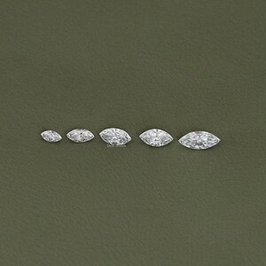 May include: Five marquise-shaped diamonds of varying sizes, arranged in a row from smallest to largest. The diamonds are clear and sparkly.