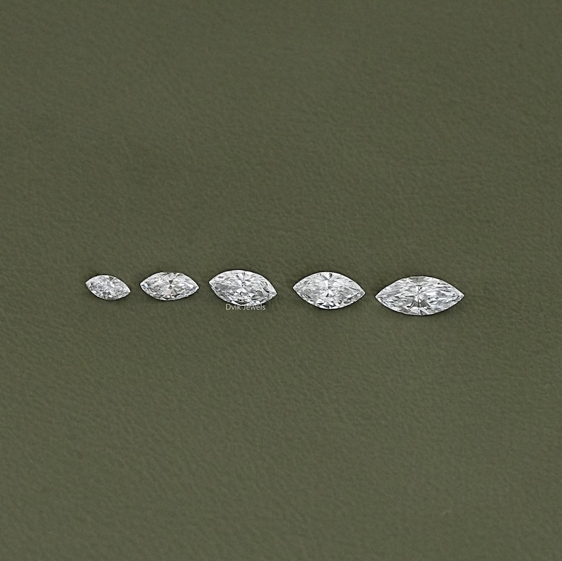 May include: Five marquise-shaped diamonds of varying sizes, arranged in a row from smallest to largest. The diamonds are clear and sparkly.