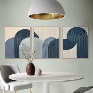 Puede incluir: Tres impresiones de arte abstracto con un esquema de color azul y verde. Las impresiones presentan una serie de arcos superpuestos con un patrón texturizado y rayado.