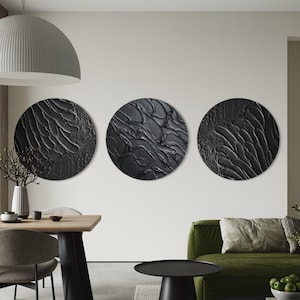 Peut inclure: Trois œuvres d'art murales rondes et texturées de couleur noire avec des motifs abstraits. L'art est monté sur un mur blanc. La pièce comprend une table à manger, un canapé vert et une table d'appoint noire.