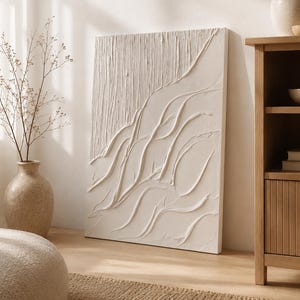 Puede incluir: Un lienzo rectangular para pared con una aplicación gruesa de pintura impasto texturizada en color blanco roto. El diseño muestra trazos lineales verticales en la parte superior izquierda que se transforman en curvas fluidas y elevadas.