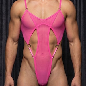 Puede incluir: Un body de malla rosa brillante con tirantes finos ajustables, un escote pronunciado y aberturas laterales conectadas por anillos metálicos plateados en forma de corazón. La prenda está confeccionada con un tejido transparente y ligero.