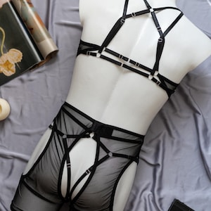 May include: Black lingerie set with a mesh bottom and a strappy top. The top has a criss-cross design at the back.