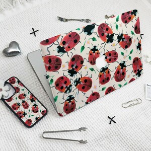 May include: A white laptop case with a red and black ladybug pattern. The case is made of a durable material and is designed to protect your laptop from scratches and bumps.