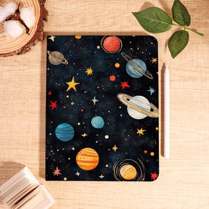 May include: A rectangular tablet case with a dark blue galaxy design. It features colorful planets, stars, and yellow accents. A white stylus is placed next to the case. The theme is space and astronomy.