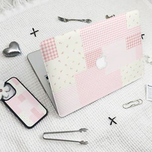 May include: A pink and white checkered laptop skin with a patchwork design. The skin is made up of different patterns, including gingham, floral, and stripes.