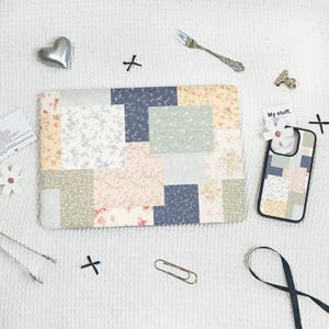 May include: A patchwork laptop sleeve and phone case with a floral pattern in pastel colors. The sleeve and case feature a mix of floral and solid fabric squares in shades of pink, blue, and beige. The phone case has the text "My stuff,"