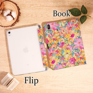 May include: An iPad with a floral print case, next to the case cover. The case features a colorful floral pattern with pink, yellow, and blue hues. The word "Book" is above the case, and the word "Flip" is below the iPad.