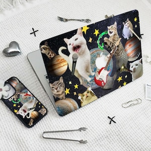May include: A black laptop case with a colorful design featuring cats, planets, stars, and musical instruments. The design includes a cat playing a guitar, a cat singing into a microphone, and a cat playing a tambourine.
