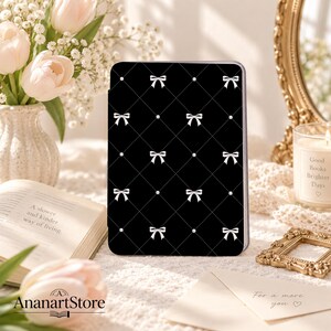 May include: A black tablet case featuring a white diamond grid pattern with small white bows at each intersection. The design is uniform across the front surface, showcasing a repeating motif of delicate bows and thin dashed lines.