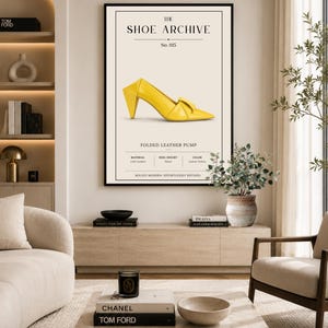 May include: A framed wall art print titled The Shoe Archive No. 015, featuring a bright yellow pointed-toe pump with a folded design. The text includes FOLDED LEATHER PUMP, MATERIAL Calf Leather, HEEL HEIGHT 70mm, COLOR Lemon Yellow, and BOLDLY MODERN.