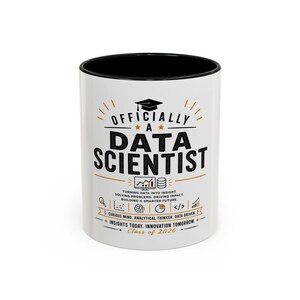 Pode incluir: Uma caneca de cerâmica branca com interior e borda pretos, apresentando o texto "OFFICIALLY A DATA SCIENTIST" em preto e laranja. O design inclui um ícone de capelo, gráficos de dados e o texto "Class of 2026" junto com outras frases.