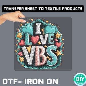 May include: A gray iron-on transfer sheet featuring the phrase "I LOVE VBS" in a colourful, hand-drawn style, with hearts and flowers. The text "TRANSFER SHEET TO TEXTILE PRODUCTS" is at the top, and "DTF- IRON ON" is at the bottom.