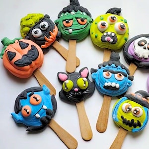 Può includere: Un set di dieci cake pops a tema Halloween. I cake pops sono decorati con vari personaggi, tra cui una zucca, un fantasma, un vampiro, un gatto, un mostro e uno zombie. I cake pops sono su bastoncini di legno e sono pronti per essere gustati.