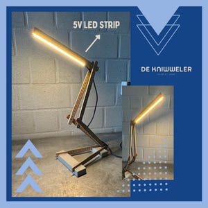 May include: A handmade desk lamp with a warm LED light strip. The lamp is constructed from wood and measuring sticks, with the text "5V LED STRIP" and the logo "DE KNIWWELER MADE AT HOME" visible.