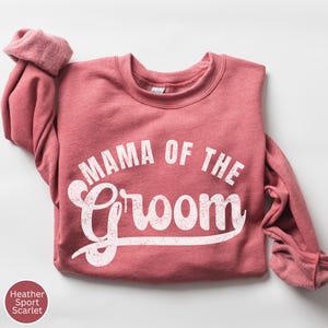 May include: A heather sport scarlet sweatshirt with the text "Mama of the Groom" in white.