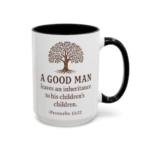 Könnte beinhalten: Weißer Keramikbecher mit schwarzem Innenraum und Henkel. Der Becher zeigt eine braune Baumgrafik und den Text "A GOOD MAN leaves an inheritance to his children's children. -Proverbs 13:22."