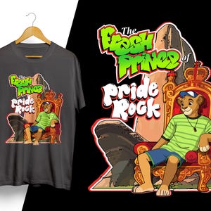 May include: Dark gray t-shirt featuring a cartoon lion wearing a hat and sitting on a throne. The shirt design includes the text "The Fresh Prince of Pride Rock" in green and white, with a matching graphic on the shirt.