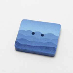 Può includere: Bottone quadrato con un design paesaggistico nei toni del blu. Il bottone presenta un motivo a catena montuosa a strati e due fori per cucire. Il bottone è realizzato in un materiale solido ed è adatto a vari progetti di cucito.