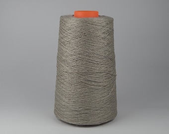 May include: A large spool of gray yarn with an orange core. The yarn is tightly wound, creating a conical shape. The neutral color of the yarn makes it suitable for various crafting projects. The spool is set against a plain gray background.