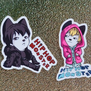 May include: Two stickers featuring cartoon characters with dog-like features. One character is in black attire, the other in a pink hoodie. Both stickers have the text "HIP HOP MONSTER" in red and blue.