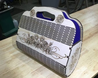 Puede incluir: Un bolso de mano de madera con un diseño floral y un forro de terciopelo azul. El bolso tiene un asa y está hecho de madera cortada con láser.
