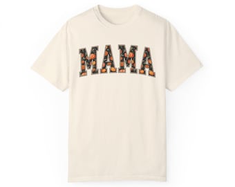 May include: A cream colored t-shirt with a black outline of the word "MAMA" filled with a pattern of orange and green pumpkins.