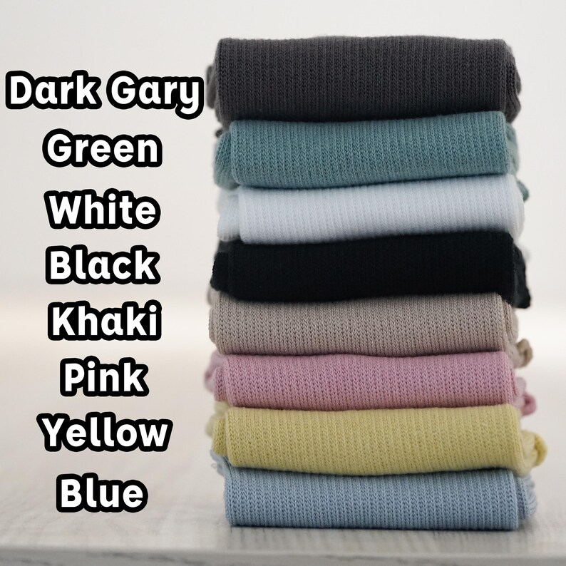 May include: A stack of 10 fabric swatches in various colours, including dark grey, green, white, black, khaki, pink, yellow, and blue. The swatches are arranged from darkest to lightest.