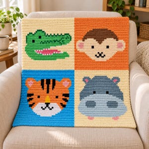 May include: A square crochet blanket divided into four panels, each featuring a different animal face: a green crocodile on cream, a brown and tan monkey on orange, an orange and black tiger on blue, and a gray hippo on a cream background.