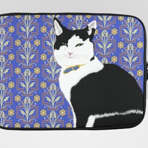 May include: A black and white cat illustration on a laptop sleeve. The sleeve has a blue background with a floral pattern. The cat is wearing a blue collar. The sleeve has a black zipper.